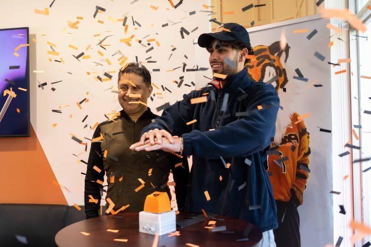 a student pushes a button while confetti comes down around him